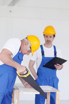 Male worker sawing a wooden board at work