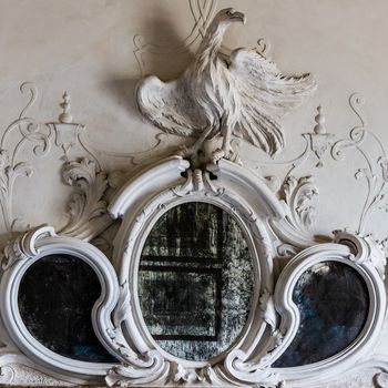Ornamental mirror above the fireplace of a Venetian villa with sculpture of a phoenix.