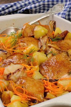 Braised roast chicken with potatoes, carrots and shalott in ceramic roasting pan