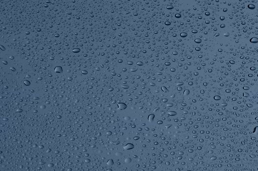 Covered with droplets of water, dark blue-gray glass.