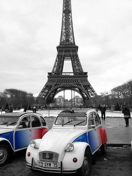 Paris, France - March 13, 2013: 2CV Cocorico Tricolor Cars. Two Citroen 2CV Parked on Front of the Eiffel Tower in Paris, France