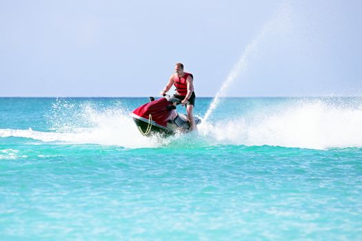 Young guy cruising on a jet ski on the caribbean sea