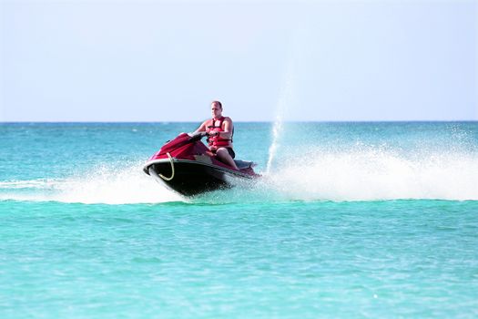 Young guy cruising on a jet ski on the caribbean sea
