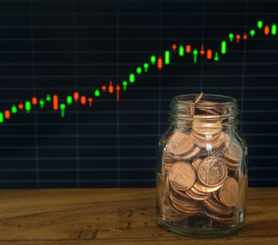 golden coins jar  on the financial stock charts as background.
