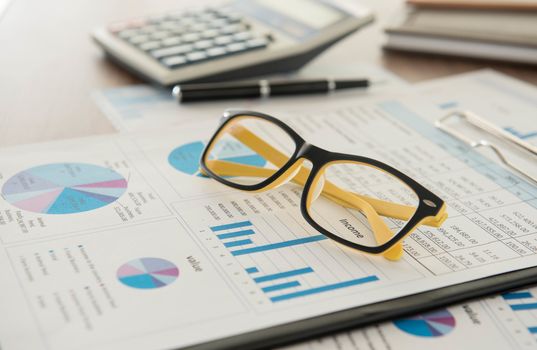 Marketer's desk with analysis Report ,Calculator, glasses.
