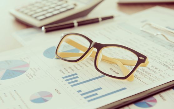 Marketer's desk with analysis Report ,Calculator, glasses.