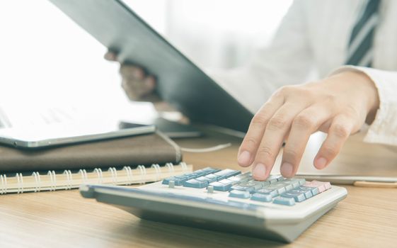 Businessman using a calculator to calculate the numbers