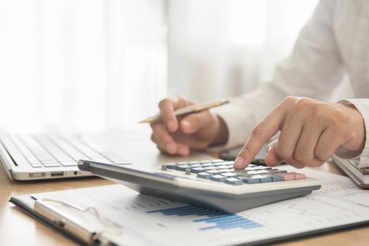Businessman using a calculator to calculate the numbers