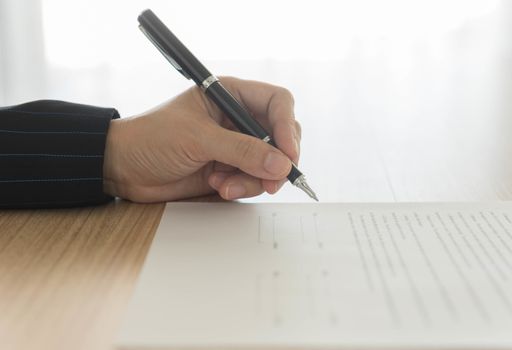 hand holding a pen to sign approval  about to sign a letter