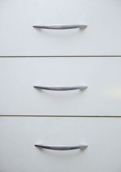 Cabinet with sliding trays and chrome handles. Close-up