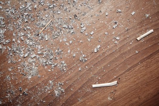 Cigarette ash on a dirty hardwood floor