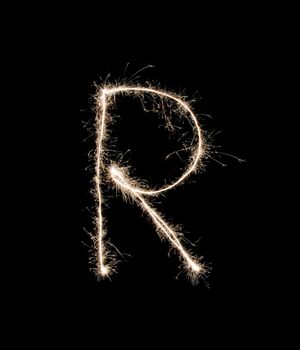 Letter R drew with spakrs on a black background.