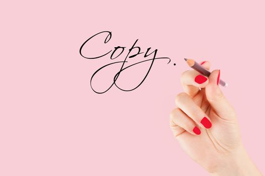 Creative industries. Female hand with pencil writng the word copy in caligraphy. Copy writing.