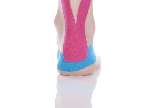 Kinesio tape on female heel isolated on white background. Chronic pain, alternative medicine. Rehabilitation and physiotherapy.