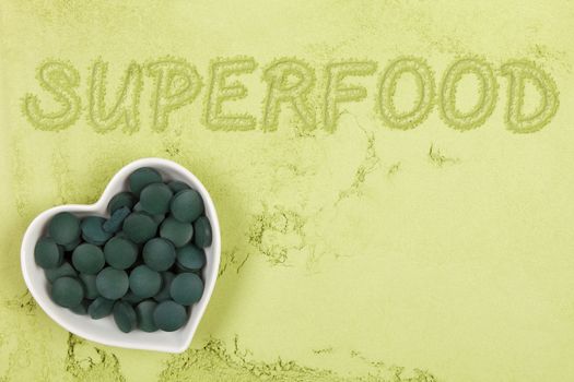 Green food supplement. Word superfood written in green ground powder, top view. Healthy lifestyle.