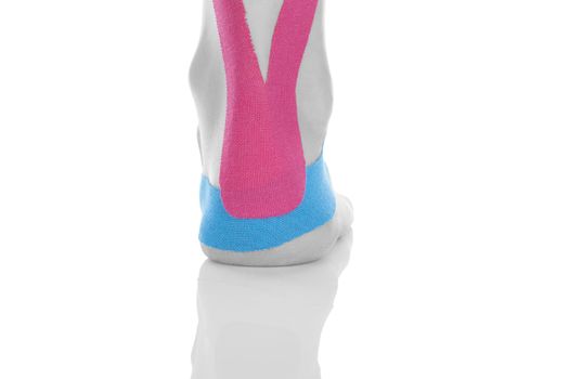 Kinesio tape on female heel isolated on white background. Chronic pain, alternative medicine. Rehabilitation and physiotherapy.