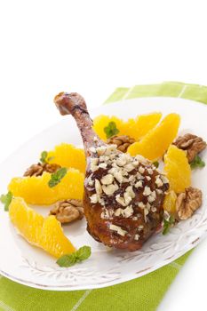 Culinary roast duck with oranges and nuts on plate isolated on white background. Delicious festive eating. 