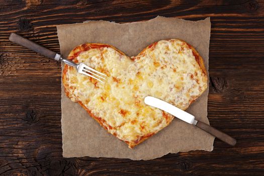 Delicious pizza in heart shape on wooden table, top view. Culinary pizza eating. I love pizza.