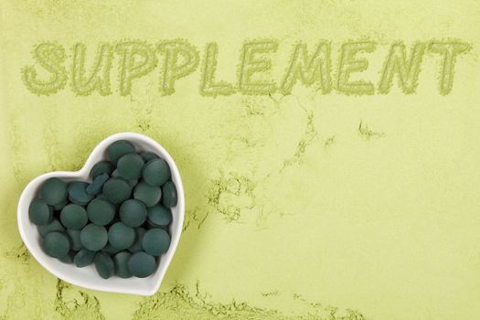 Dietary supplement. Green food supplement. Word supplement. written in green ground powder, top view. Healthy lifestyle.