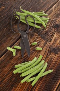 Raw fresh green beans with water drops on brown wooden textured table. Fresh vegetable eating. 