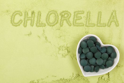 Green food supplement. Word chlorella written in green ground powder, top view. Healthy lifestyle.