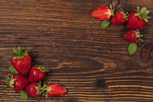 Ripe strawberries on rustic wooden brown table, flat lay. Strawberry background with copyspace. Healthy fruit eating.