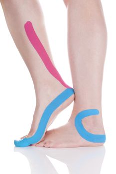 Kinesio tape on female leg isolated on white background. Chronic pain, alternative medicine. Rehabilitation and physiotherapy.