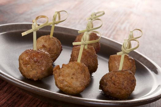 Meatballs canape on brown plate on brown wooden background. Culinary bbq eating. 
