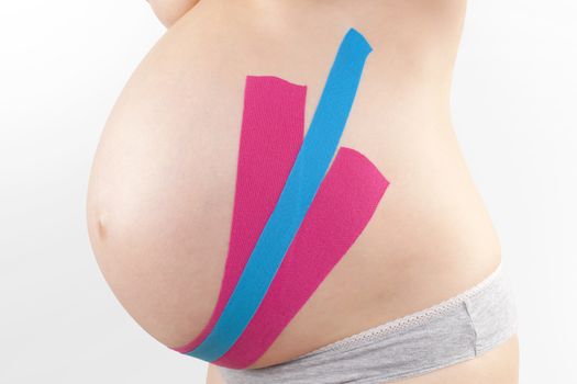 Beautiful pregnant woman with kinesio tape. Back pain in pregnancy, alternative kinesio tape therapy.