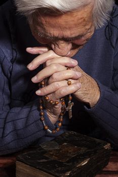 Grandmother praying. Old wrinkled beautiful woman praying with rosary. Faith, spiritualy and religion.