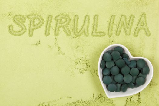 Spirulina. Green food supplement. Word spirulina written in green ground powder, top view. Healthy lifestyle.