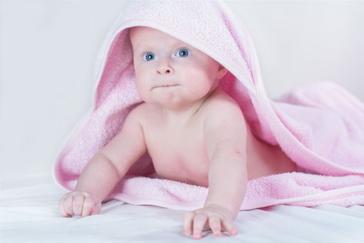 Sweet small baby covered with a rose towel with big eyes