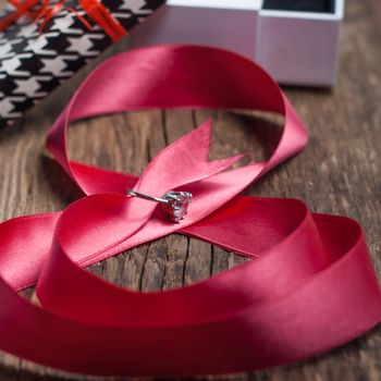 Beautiful pink ribbon with a ring on a wood background, greetings on happy women's day