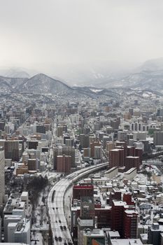 View from above down towards highway and buildings in Sapporo, Japan under overcast winter skies