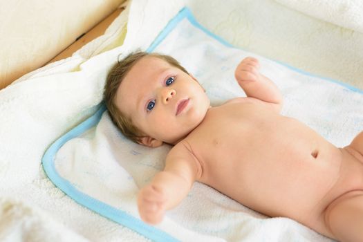 A Infant lying on a white towel .