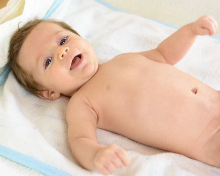 A smiling Infant lying on a white towel .