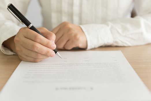 hand holding a pen to sign approval  about to sign a letter