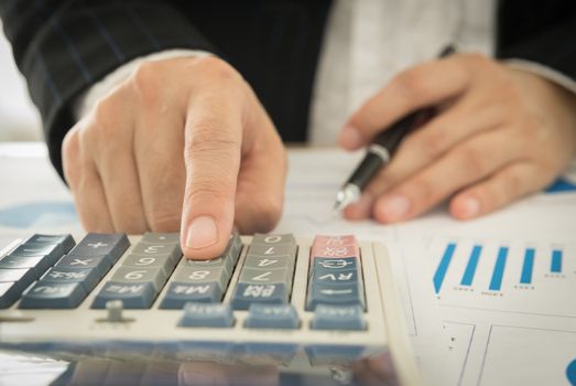 Businessman using a calculator to calculate the numbers