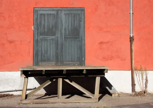 Old Wooden Cargo Ramp with Shadow and Red Wall