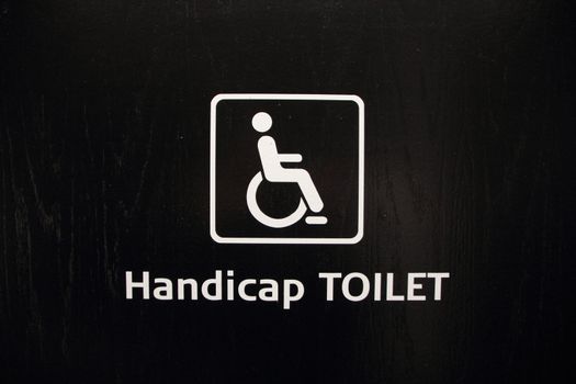 Isolated White Handicap Disabled Toilet Sign on Black Wood