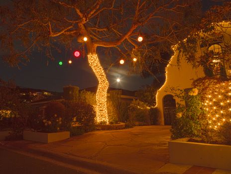Full moon peaks through a tree with Christmas lights and balls in Laguna Beach, California