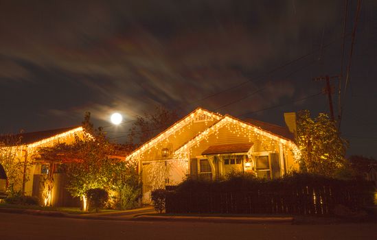 Laguna Beach, California, December 25, 2015: A full moon peaks over a home with Christmas lights in Laguna Beach, California. There has not been a full moon at Christmas since 1977. The next one won’t be until 2034