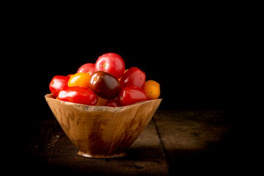Bowl of fresh heirloom tomatoes on a low key background suitable for many food services purposes.