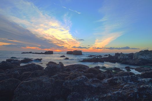 Long exposure of sunset over rocks, giving a mist like effect over ocean in Laguna Beach, California, United States