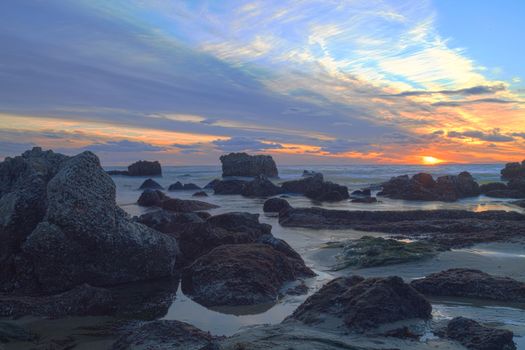 Long exposure of sunset over rocks, giving a mist like effect over ocean in Laguna Beach, California, United States