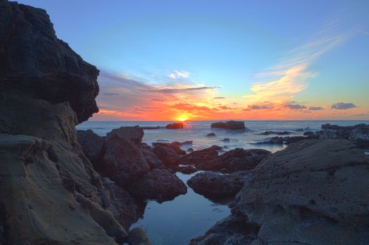 Long exposure of sunset over rocks, giving a mist like effect over ocean in Laguna Beach, California, United States