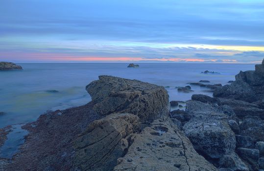 Long exposure of sunset over rocks, giving a mist like effect over ocean in Laguna Beach, California, United States