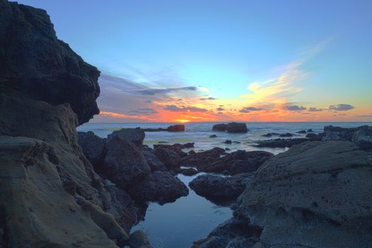 Long exposure of sunset over rocks, giving a mist like effect over ocean in Laguna Beach, California, United States