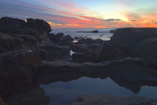 Long exposure of sunset over rocks, giving a mist like effect over ocean in Laguna Beach, California, United States