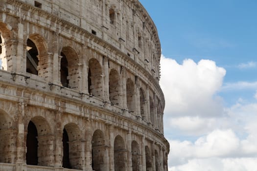 Close up detailed view of ancient amphitheatre of Colosseum built by Vespasian and Titus in Rome, on cloudy sky background.